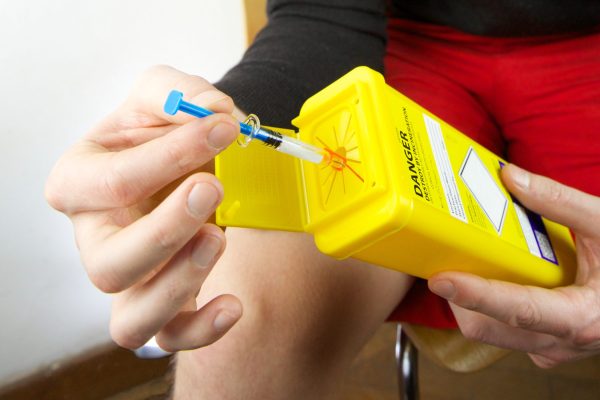 person reviewing sharps bin for disposal of needles - after self-administering an injection